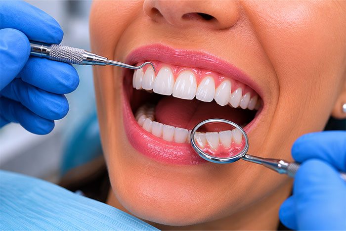 Dentist examining gums with mirror and scaler during periodontal maintenance